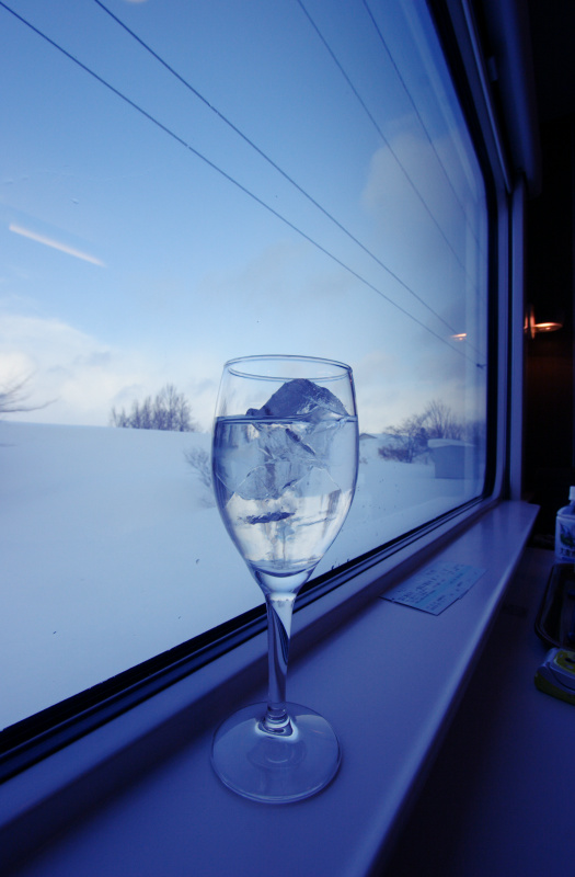 雪原を走る列車の窓辺に置かれたワイングラス